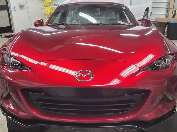Red Mazda C5 with paint protection film on on hood of car